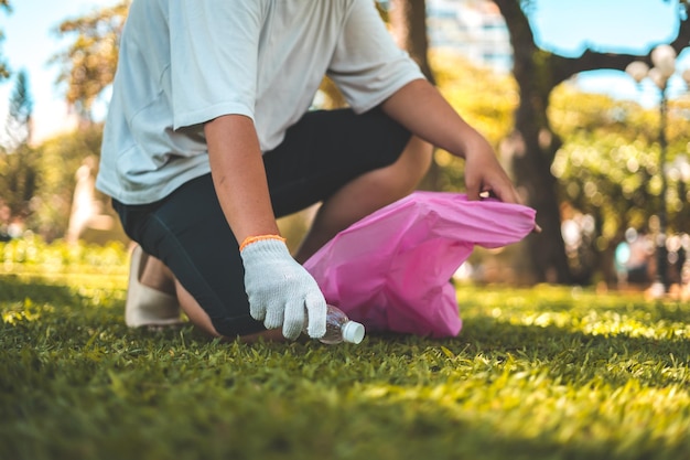 Focus Hombre voluntario con guantes recogiendo basura de botellas en la playa del parque Limpieza de la naturaleza