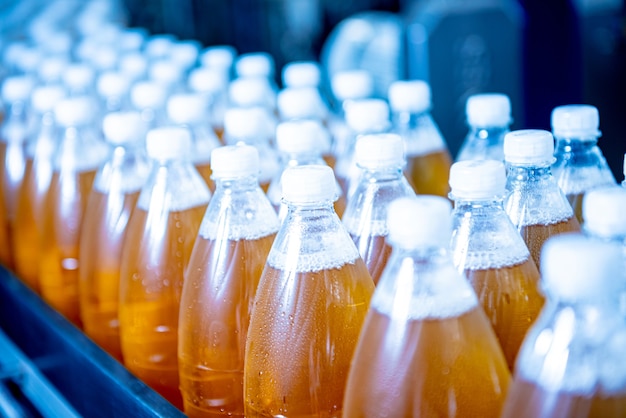 Förderband mit Flaschen für Saft oder Wasser in einer modernen Getränkefabrik