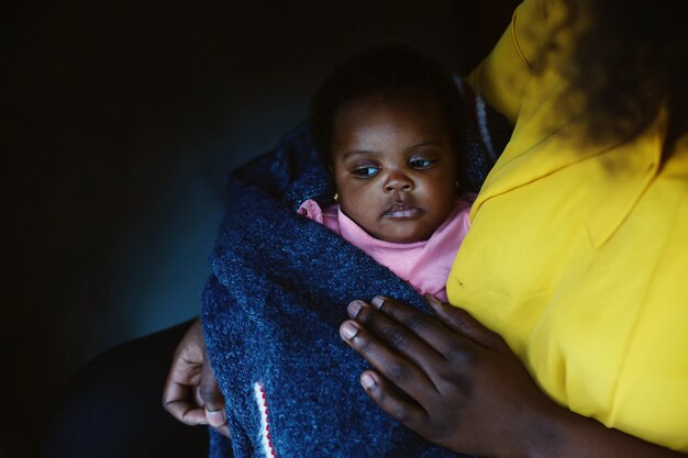 Fofo bebê afro-americano sério nas mãos de mães