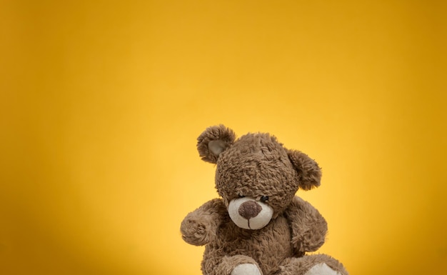 Fofo urso de pelúcia marrom com manchas em um fundo amarelo, brinquedo infantil