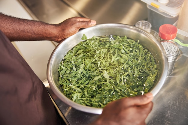 Fogão afro-americano lavando verdura em uma tigela na cozinha