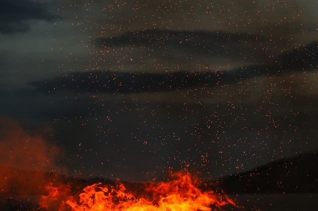 Fogo contra o céu nublado à noite
