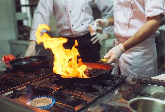 Fogo na cozinha. Queima de gás de fogo está cozinhando na panela de ferro, mexa fogo muito quente