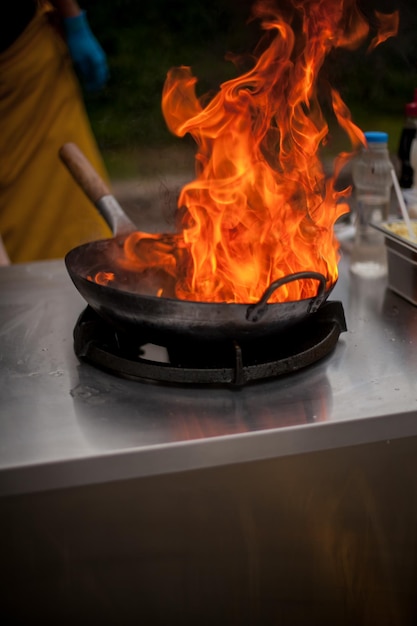 Foto fogo na panela chef profissional em uma cozinha comercial cozinhando estilo flambe chef flambe cooking