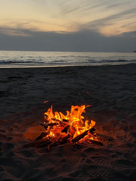 Foto fogo na praia contra o céu durante o pôr-do-sol