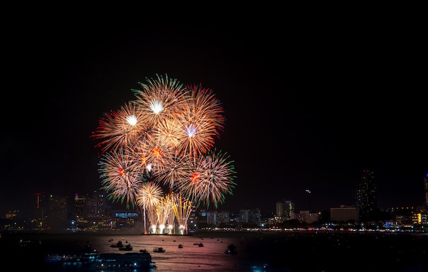 Fogos de artifício explorados ao longo da paisagem urbana à noite no porto de mar em Pattaya.