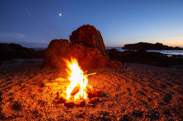 Fogueira de acampamento na praia durante um pôr do sol de verão vibrante