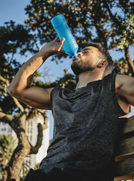 Foi um treino e tanto Foto de baixo ângulo de um jovem esportivo bebendo água enquanto se exercitava ao ar livre