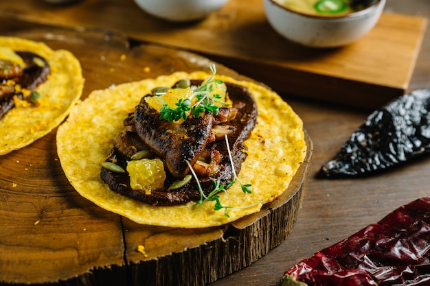 Foie gras tacos servido na tábua de madeira.