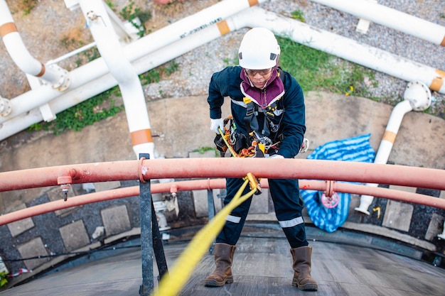 Fokus Draufsicht männlicher Arbeiter nach unten Höhe Tankdach Seilzugang Sicherheitsinspektion von Dicke Lagertank Rohöl