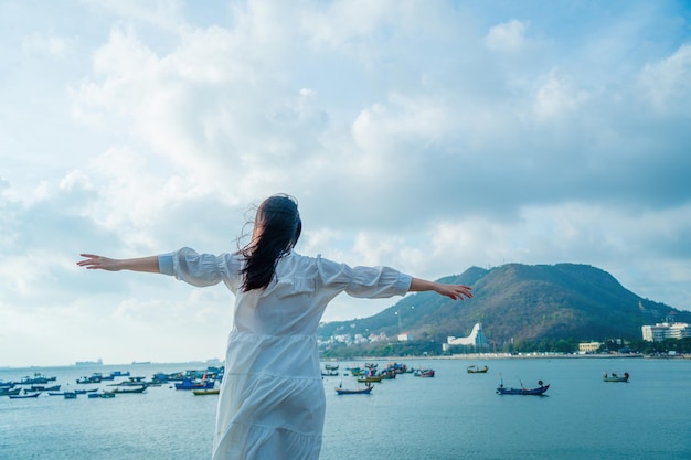 Fokus Rückansicht glückliches asiatisches Mädchen hebt ihre Hände vor dem Strand von Vung Tau Travel Concept