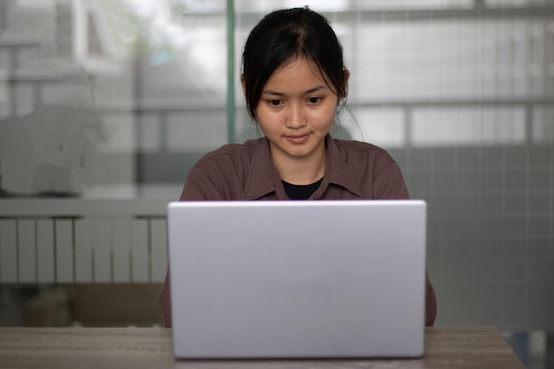 Fokussierte asiatische Frau, die tagsüber Laptop im Büro verwendet