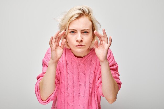 Fokussierte Frau in rosa Pullover mit konzentriertem Gesichtsausdruck versucht, ein Gespräch zu hören