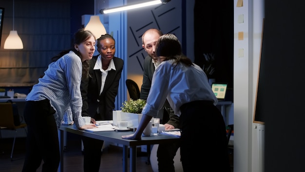 Fokussierte Geschäftsfrau betritt den Besprechungsraum im Büro, der am Konferenztisch steht und die Präsentation des Unternehmens spät in der Nacht plant