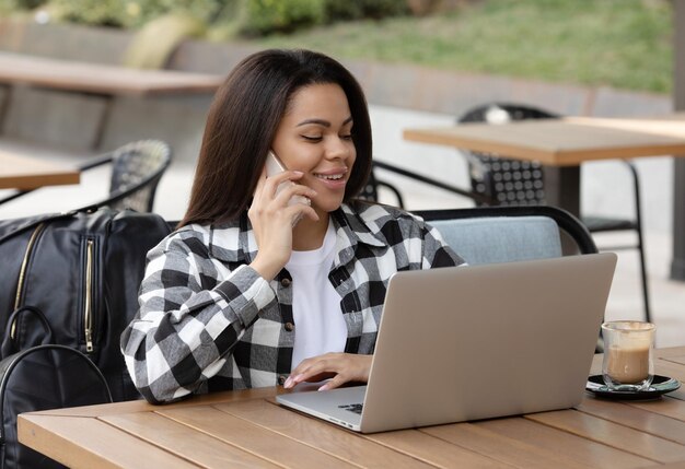 Fokussierte junge Afrikanerin, die allein an einer Theke in einem Café sitzt und an einem Laptop arbeitet