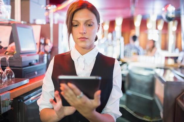 Fokussierte Kellnerin mit Touchscreen bis