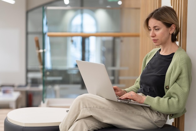 Fokussierte nachdenkliche Freiberuflerin mittleren Alters, die in der Bibliothek am Laptop arbeitet