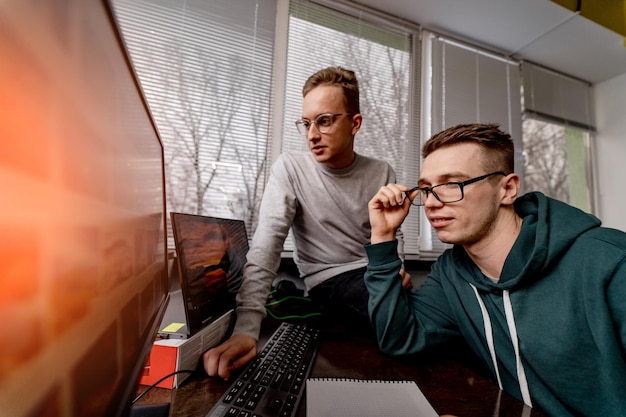 Fokussierte Studenten mit Brille, die auf den Bildschirm der Computerteamarbeit am modernen Arbeitsplatz schauen