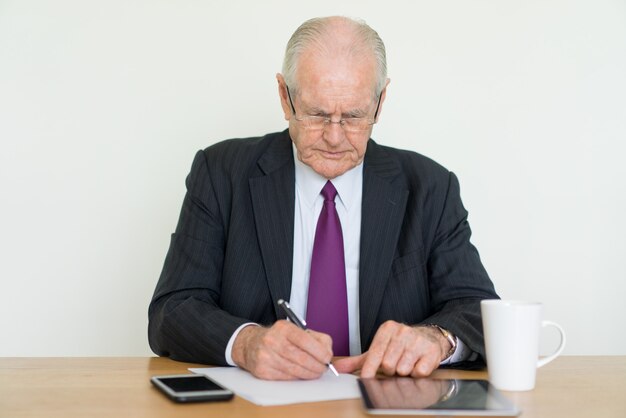 fokussierter älterer Geschäftsmann, der Tablet-Computer am Schreibtisch schreibt und verwendet