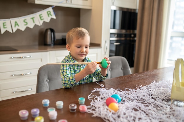 Fokussierter kreativer Junge, der Eier für Ostern verziert