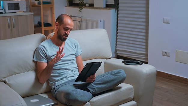 Fokussierter Mann mit Bart sitzt auf der Couch vor dem Fernseher