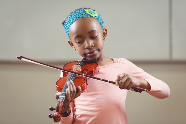 Fokussierter Schüler, der Violine in einem Klassenzimmer spielt