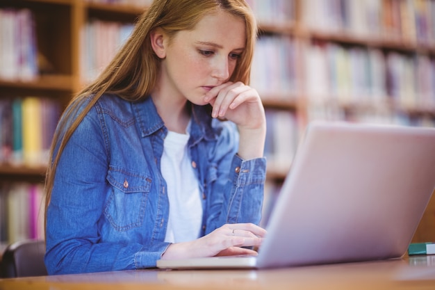 Fokussierter Student, der Laptop in der Bibliothek verwendet