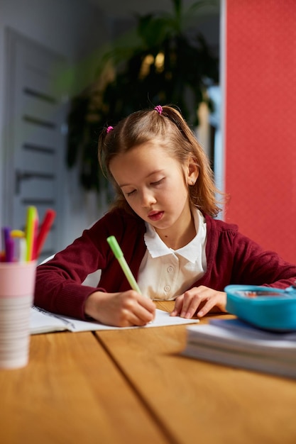 Fokussiertes Schulmädchen sitzt am Schreibtisch und macht Hausaufgaben Handschrift Homeschooling