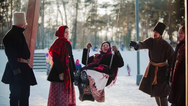 Folclore ruso mujer joven balanceándose y todos se ríen en un día soleado