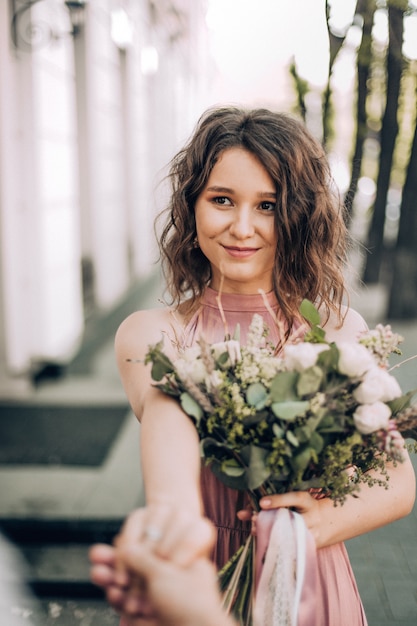 Folge mir! Foto mit Braut im rosa Kleid mit einem Blumenstrauß