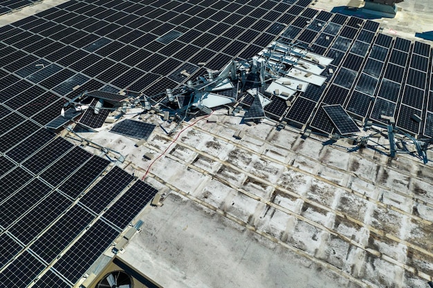 Folgen einer Naturkatastrophe Beschädigung durch Hurrikanwind Photovoltaik-Solarpaneele, die auf dem Dach eines Industriegebäudes montiert wurden, um grünen ökologischen Strom zu erzeugen