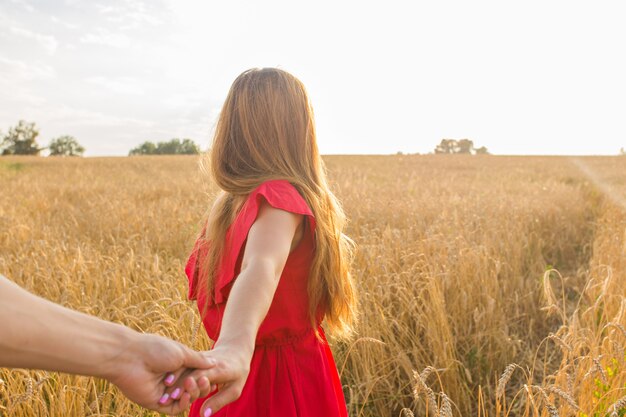 Folgen Sie mir, schöne junge Frau hält die Hand des Mannes in einem Weizenfeld