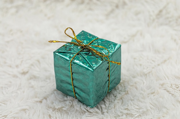 Folha brilhante verde embrulhado em caixa de presente de Natal em fundo de pele branca.