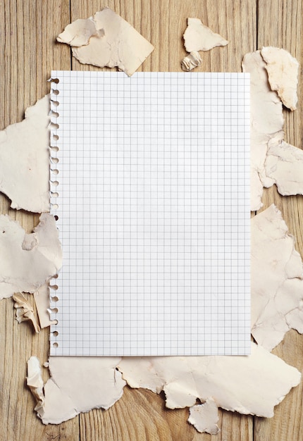 Foto folha de caderno em branco no fundo de um papel rasgado em uma mesa de madeira