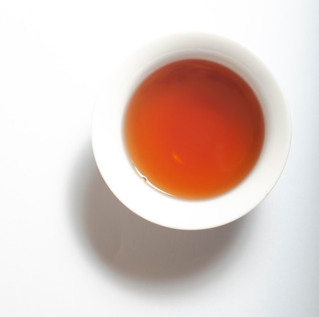 Folha de chá chinês oolong e chá oolong em xícara tradicional em branco