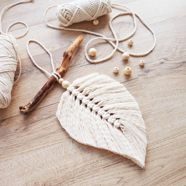 Folha de macramê em cor natural e enrolamentos de linha sobre uma mesa de madeira decoração com corda de algodão macrame para deixar seu quarto mais aconchegante e único passatempo feminino decoração artesanal para pendurar na parede espaço para texto