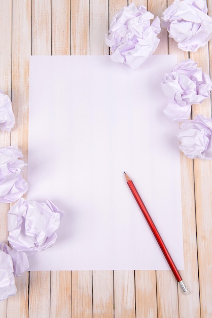 Foto folha de papel branco com papel amassado e lápis na mesa closeup