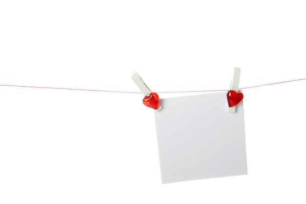 Folha de papel branco pendurada em uma corda com prendedores de roupa com um coração vermelho isolado no fundo branco