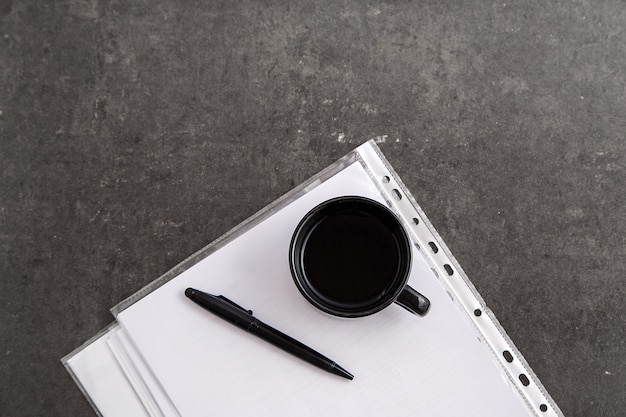Folha de papel com espaço de cópia e caneta preta com uma xícara de café