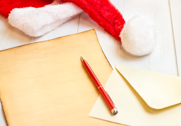 Folha de papel de chapéu de papai noel com uma caneta deitada em uma superfície branca, close-up