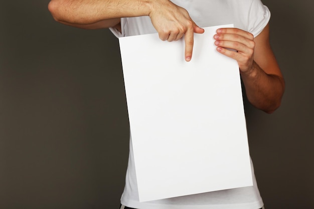 Folha de papel em branco nas mãos masculinas em fundo escuro