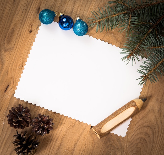 Folha de papel em branco no chão de madeira com um lápis e enfeites de Natal