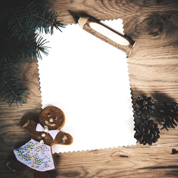 Foto folha de papel em branco sobre um piso de madeira com um lápis e decorações de natal com um homem de gengibre