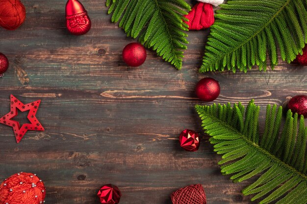 Folha de pinheiro de natal com decoração bugiganga vermelha na mesa de madeira