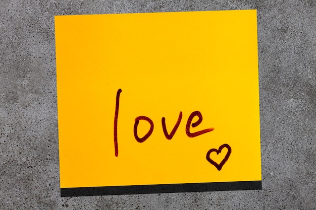 Folha pegajosa amarela na parede. marcador de inscrição palavra amor