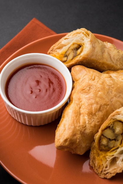 Folhada de vegetais recheados ou samosa, famoso lanche da padaria indiana, servido com ketchup de tomate e chá quente, foco seletivo