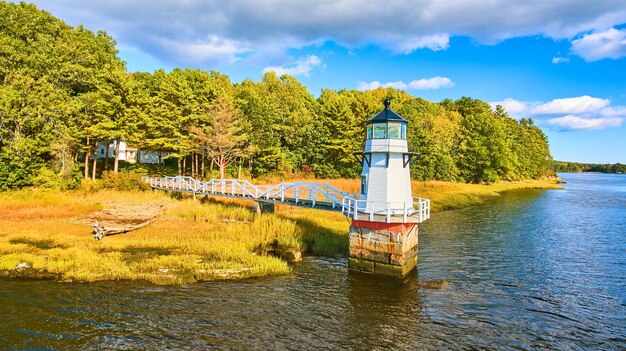 Folhagem de outono na costa com pequeno farol no Maine e passarela