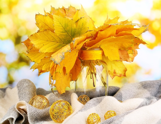 Folhas brilhantes de outono em vaso sobre mesa de madeira sobre fundo natural