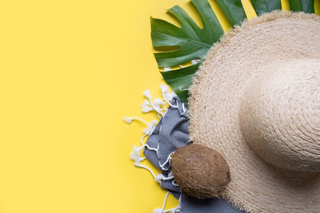 Folhas de chapéu de sol de palha de praia, cocos, conchas e monstera. Férias de verão com acessórios. Vista do topo.