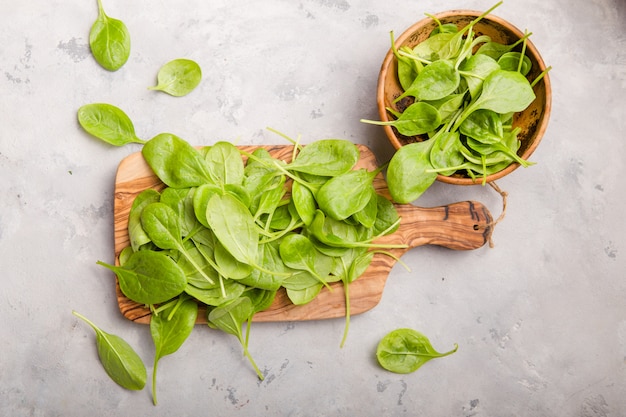 Folhas de espinafre bebê em tigela na superfície de concreto cinza. Alimentação limpa, desintoxicação, ingrediente alimentar da dieta